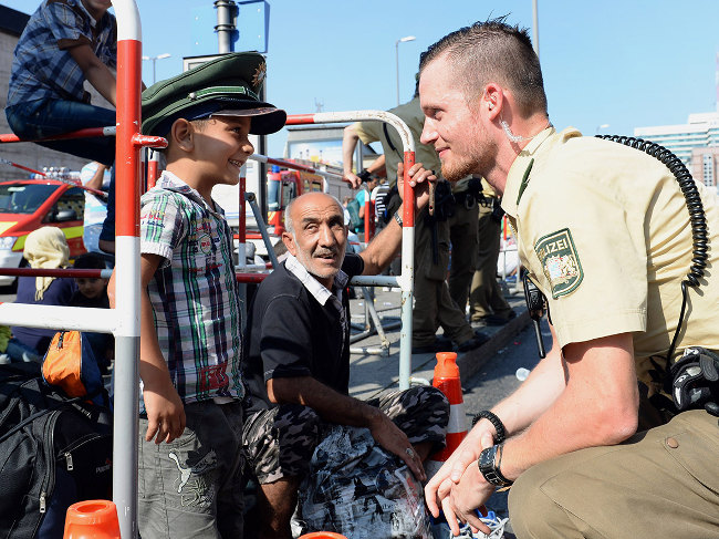 Bavarian soldier makes a young Syrian refugee boy smile as he enters Munich